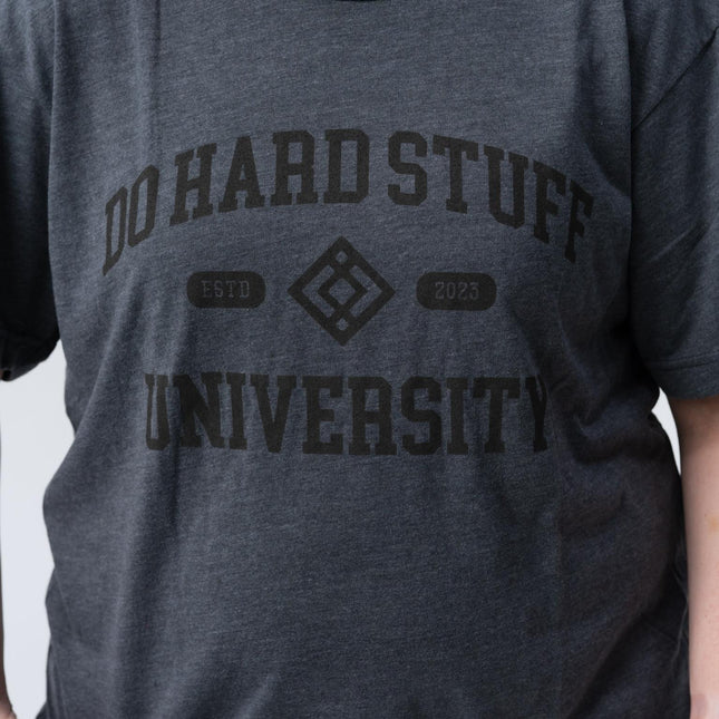 Person wearing the Do Hard Stuff Alma Mater tee, hands in pockets, front view