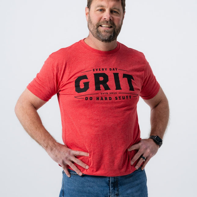 Man smiling while wearing red Do Hard Stuff Grit Tee