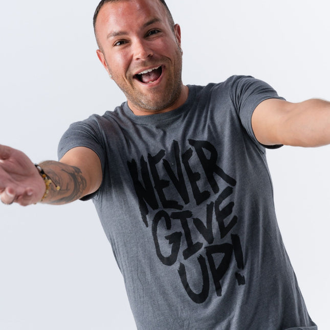 Man in Do Hard Stuff Never Give Up shirt reaching toward camera