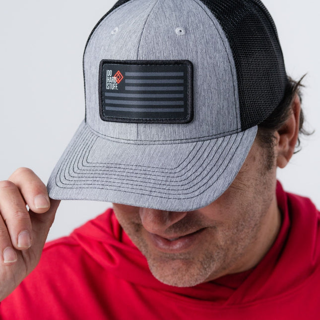 Man wearing Patriot Hat looking down and to the side, showcasing black mesh and flag patch.