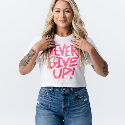 Woman adjusting her hair while modeling the Do Hard Stuff crop tee with bold pink lettering.