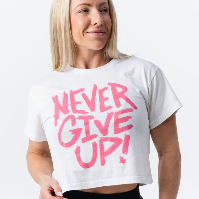 Woman in black leggings holding the hem of her Do Hard Stuff crop tee with pink message.