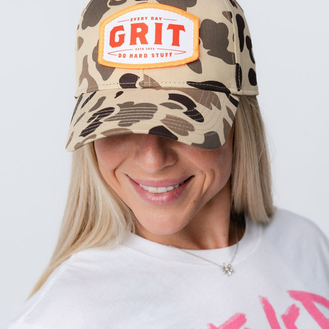 Woman smiling while wearing Grit Hat in vintage camo, showing front design and relaxed fit