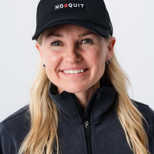 Woman wearing the black mesh No Quit Hat from Do Hard Stuff with white and red embroidered patch on front.
