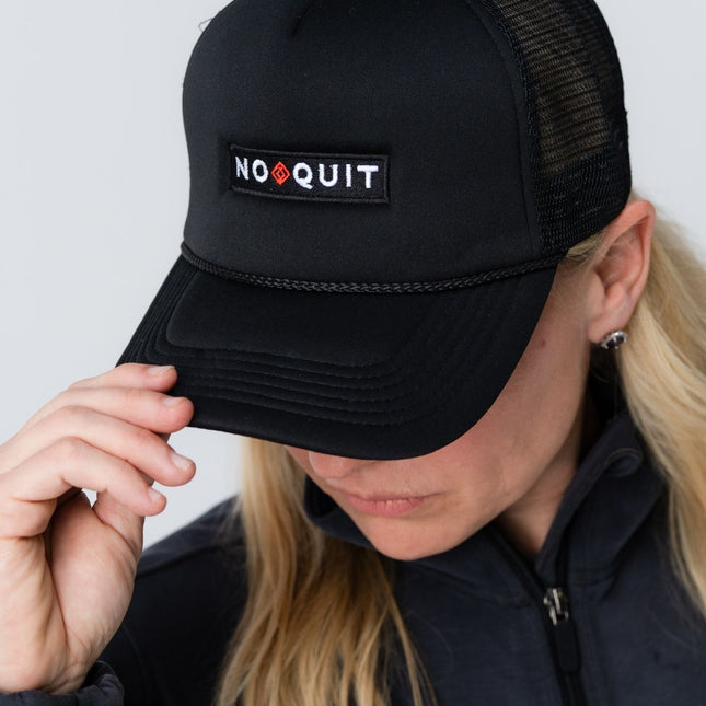 Woman tilting brim of the No Quit Hat, showcasing the side and front patch design.