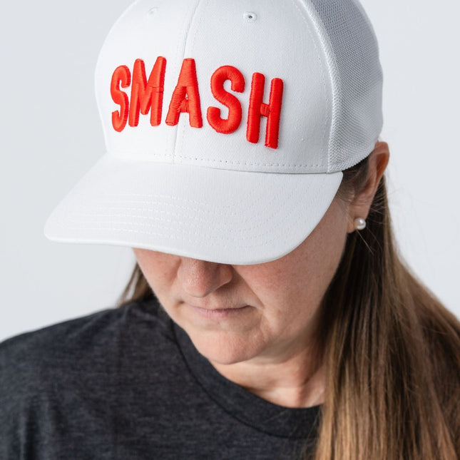Woman looking down while wearing the white Smash hat by Do Hard Stuff, showing bold orange embroidery.