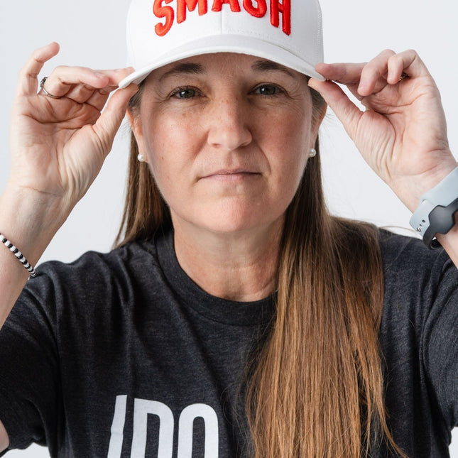 Woman wearing the white Smash hat with orange embroidery from Do Hard Stuff, front view.